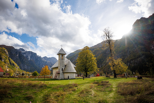 Theth, Albania - October 28 2023: The village church surrounded by the Albanian Alps in autumn colors.