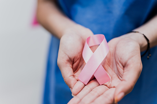 Close-up of a woman patient holding breast cancer ribbon at hospital