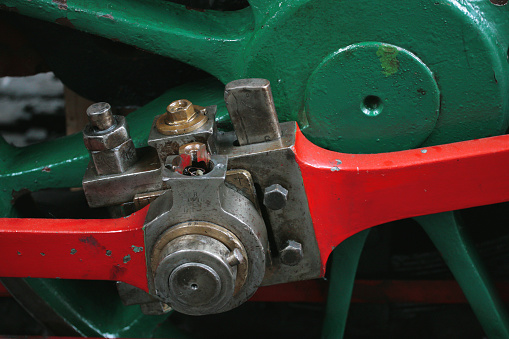 Big close-up of part of a Victorian restored steam engine, showing a driving wheel and connecting rods: Manchester, UK