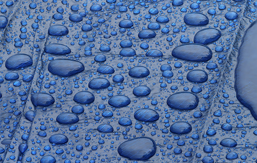 Water drops collecting on the surface of a blue tarp.