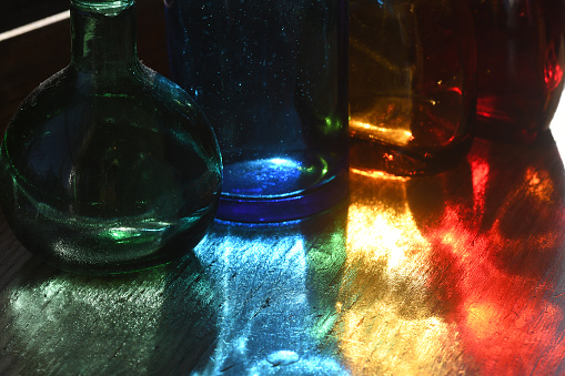 Sunlight filtering through colored glass bottles on a windowsill