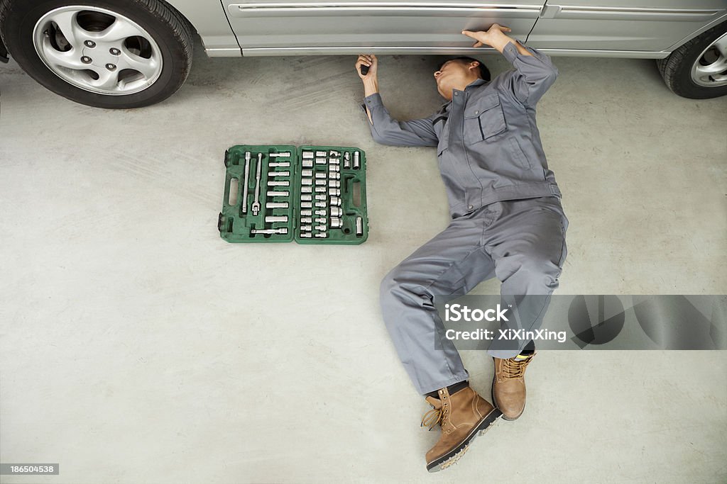 Mécanicien travaillant sur l'envers de voiture - Photo de Allongé sur le dos libre de droits