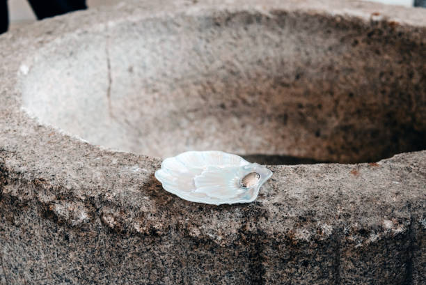 Mother-of-pearl baptismal shell on a stone baptismal font. Baptism ceremony according to Christian tradition.