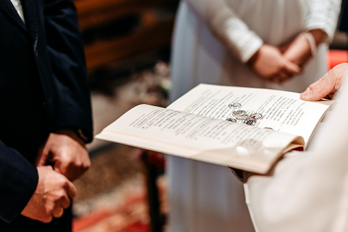 Wedding coins on an open book held by a priest at the altar during a wedding ceremony. Coins as a symbol of wealth in marriage. Christian wedding celebration