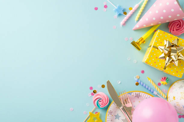 istock Joyous birthday display inspiration. Top view of table decked out with party essentials, disposable plate, candies, wrapped gift, confetti and more on soft blue surface with empty space for text 1865103697