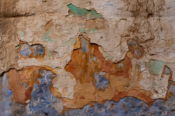 Abstract, detail, pattern of a section of multi-colored, peeling paint layers on an old stone exterior wall of a residence in Jerusalem, Israel.