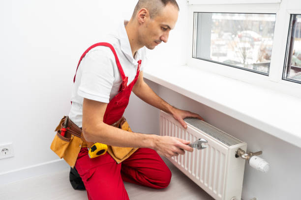 istock Professional plumber installing new heating radiator in room 1865116582