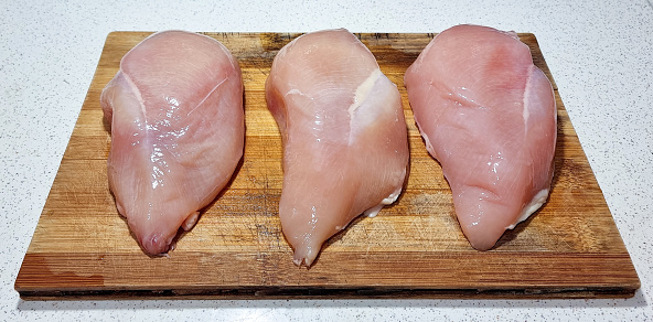 Raw chicken thighs on iron cast on grey background.