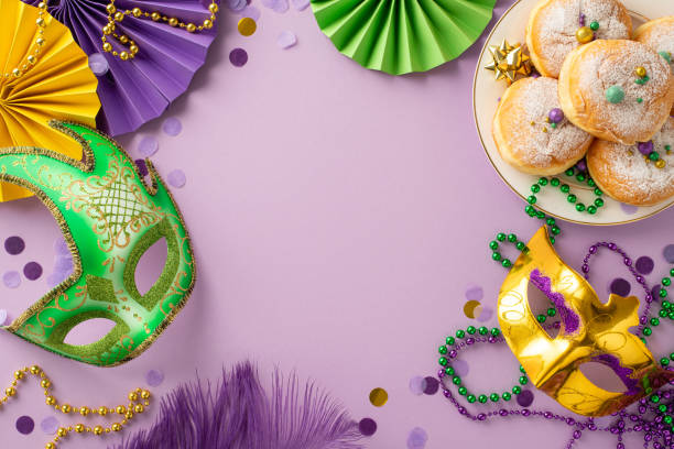 istock Jubilant Gathering Setup: Top view photo capturing table with carnival masks, feathers, fans, ribbon star, confetti, beads garlands, sweet donuts, creating lively atmosphere on purple background 1865157571