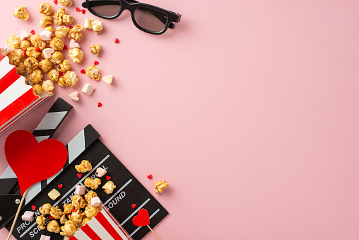 Romantic movie vibes this Valentine's. Top view capturing clapperboard, 3D specs, large popcorn boxes, heart-shaped marshmallows, sprinkles on sweet pastel pink background, creating dreamy atmosphere