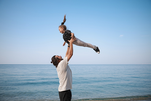 Airplane, love and father with girl at beach for travel, freedom or happy family vacation in summer with fun. Flying, care and man parent with kid at sea for piggyback,