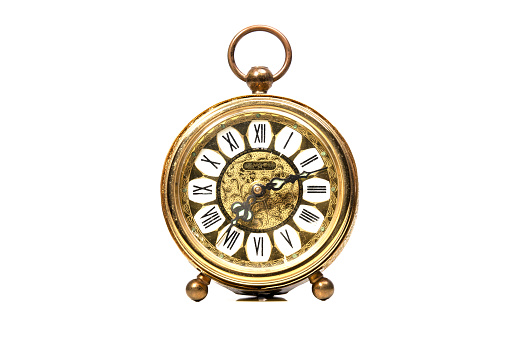 an old golden analog alarm clock with mechanical movement isolated on a white background