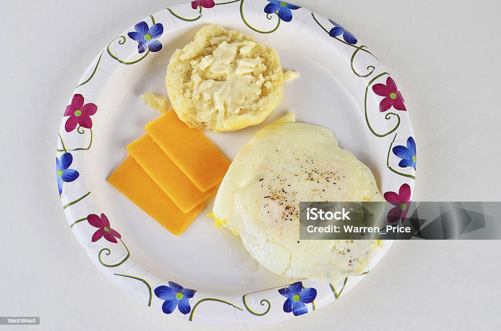 Fried Egg on Biscuit Fried egg on baked biscuit with butter and cheese on paper plate. Baked Stock Photo