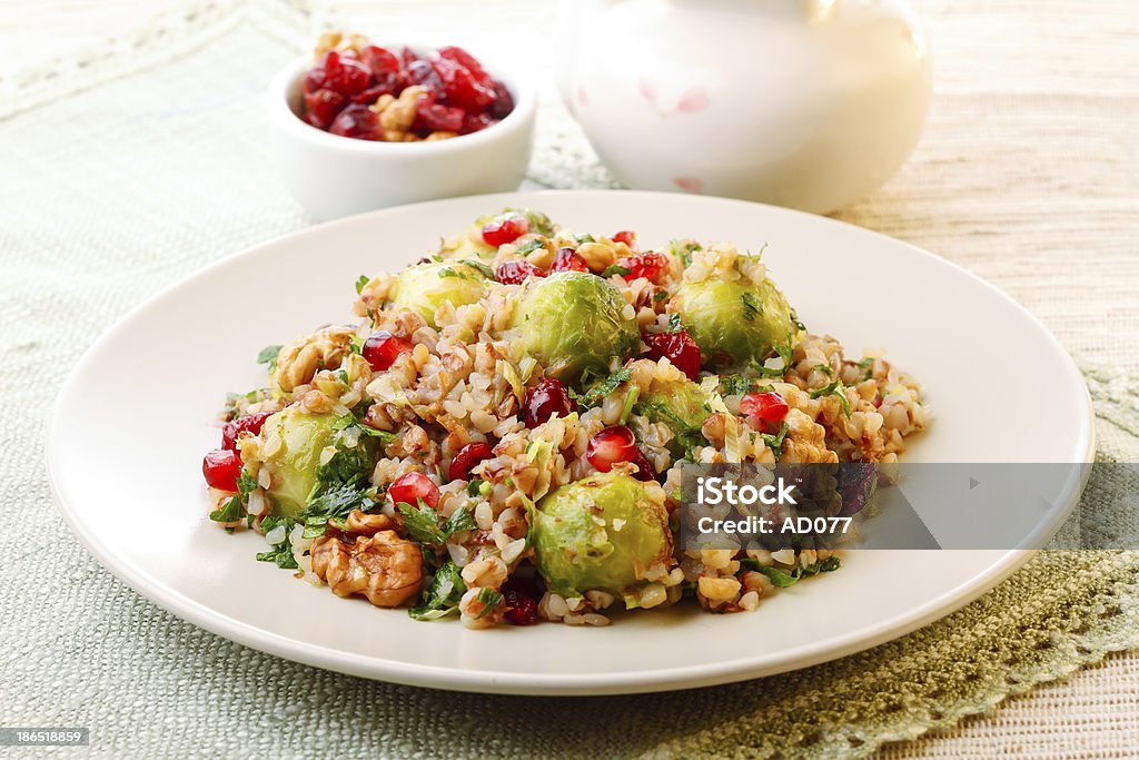 A plate full of warm buckweat salad with brussel sprouts Warm buckwheat salad with roasted brussel sprouts, walnuts and dried cranberries Appetizer Stock Photo