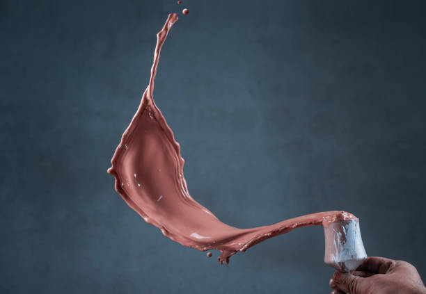 istock Throwing brown paint splash onto wall - artist working at studio 1865208939