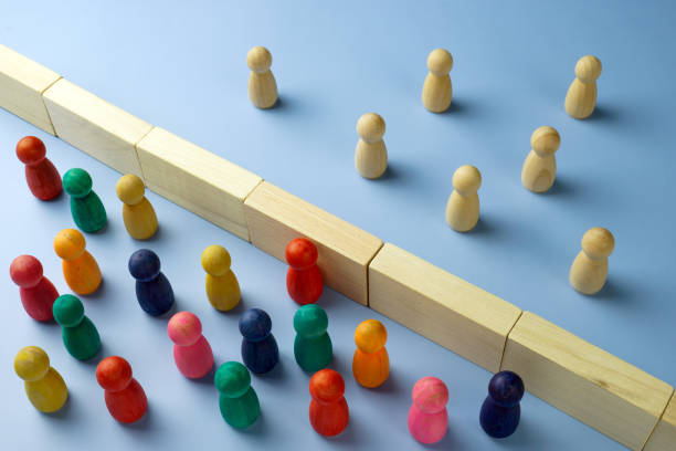 istock Diversity and immigration. Multi-colored figures are separated from wooden ones by a wall. 1865233541