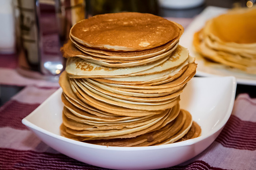 Stack of pancakes in a white plate on a table. Shallow depth of field