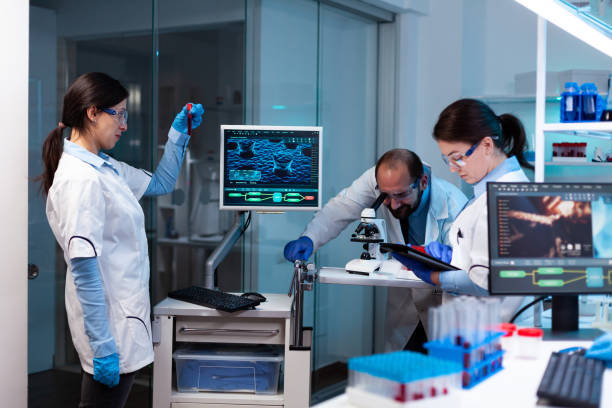 istock Scientist analyzing blood sample in vacutainer with researching team 1865342018