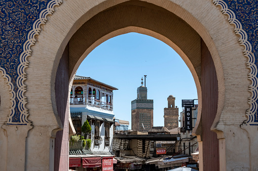 Fez, Morocco - may 16, 2023: view of the minarets of the Medersa Bou Inania through the Bab Boujeloud gate, the main entrance to the ancient medina souk in Fez Morocco.