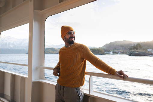 model man on sea adventure in a boat crossing the fjords while enjoying the views on his holidays