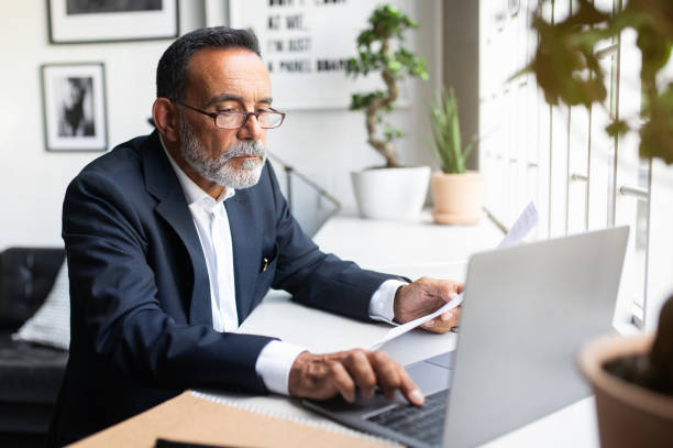 istock Serious concentrated caucasian senior businessman in suit with contract types on computer, work remotely 1865408616