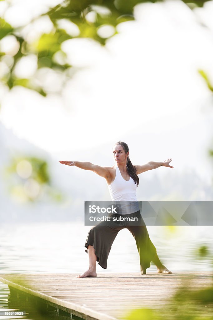 Warrior pose during yoga exercise Female posing the warrior yoga pose at the lake. 30-39 Years Stock Photo