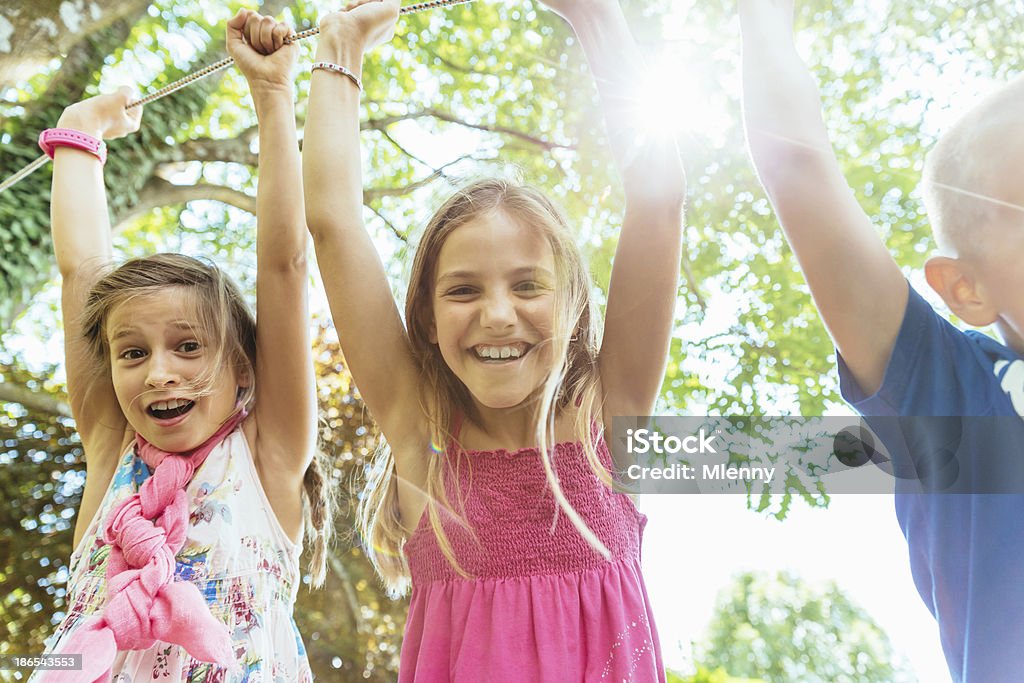 Children on Playground Having Fun Three happy kids, boy and two girls, playing outdoors on a playground. Friends having fun during summer. 10-11 Years Stock Photo
