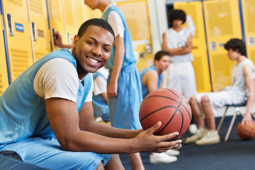 Happy high school basketball player in locker room after game