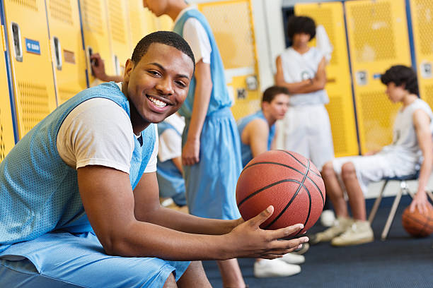 Happy high school basketball player in locker room after game Happy high school basketball player in locker room after game teenagers only teenager multi ethnic group student stock pictures, royalty-free photos & images