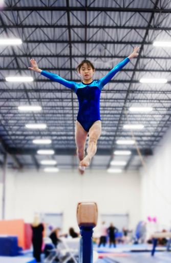 Young Asian girl performs balance beam routine.