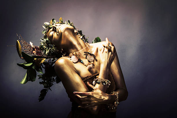 Gold Woman Attractive female painted gold,wearing jewelry and branches on her head.Studio creative shot. body paint photos stock pictures, royalty-free photos & images