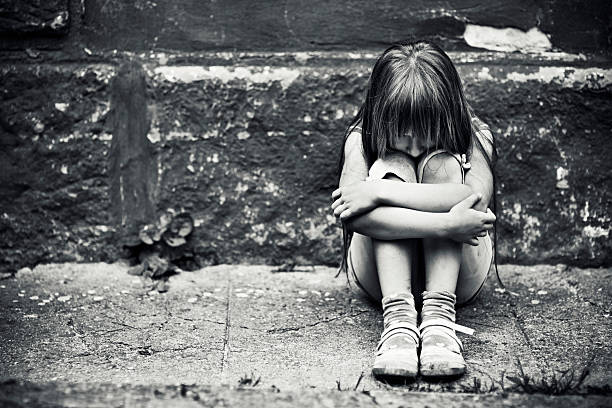 Depressed little girl Depressed child sitting at weargered sidewalk. Fine noise applied. poverty stock pictures, royalty-free photos & images