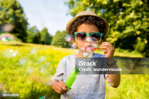 istock Child blowing bubbles in park 186543898