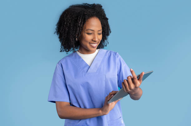istock Glad black millennial lady nurse in uniform typing on tablet, work with technology 1865439892