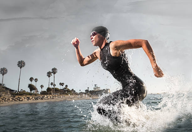 atleta di triathlon femminile correre fuori dall'acqua - competitive sport competition swimming wetsuit foto e immagini stock