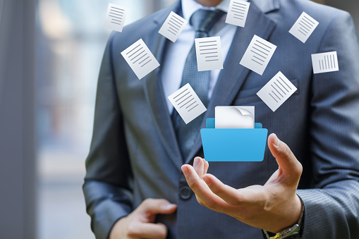 A businessman shows a folder with documents on a blurred background.