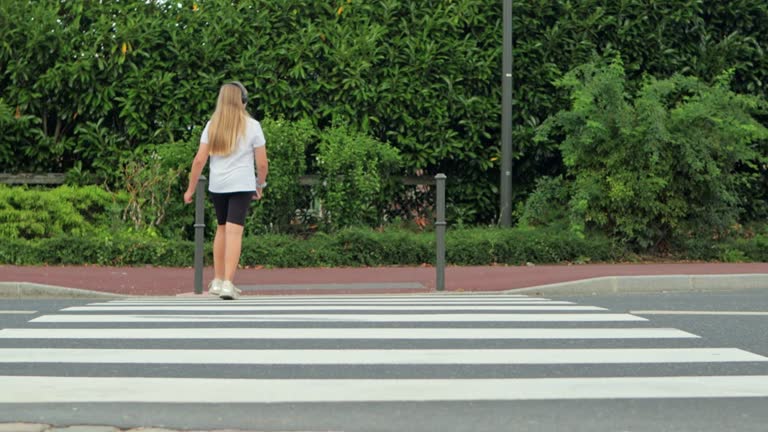 teenage girl in headphones cheerfully skips the road through a pedestrian crossing