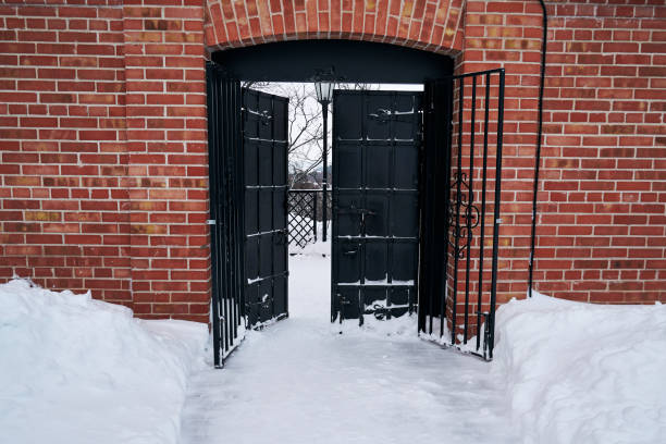 istock Black iron gate in a brick wall in winter 1865472409