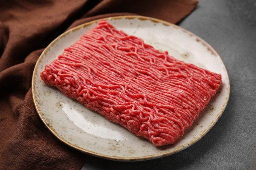 Fresh raw ground meat on brown textured table, closeup
