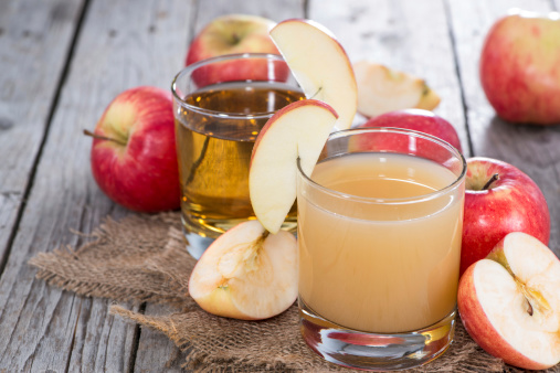 Small Glass with fresh Apple Juice on wooden background