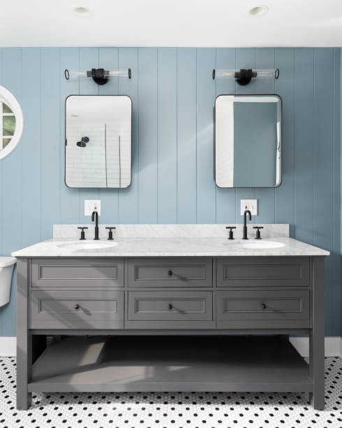 A blue bathroom with a grey cabinet and black and white tile floor.