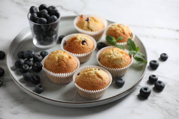 istock Delicious sweet muffins with blueberries and mint on white marble table 1865494957
