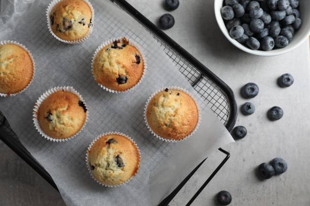 istock Delicious sweet muffins with blueberries on grey table, flat lay 1865496022