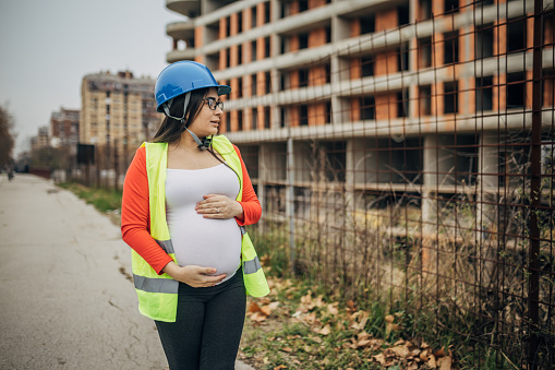 A young beautiful pregnant woman supervises work on the construction site