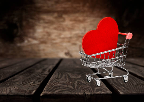 istock Red heart in mini grocery cart on wooden table 1865513993