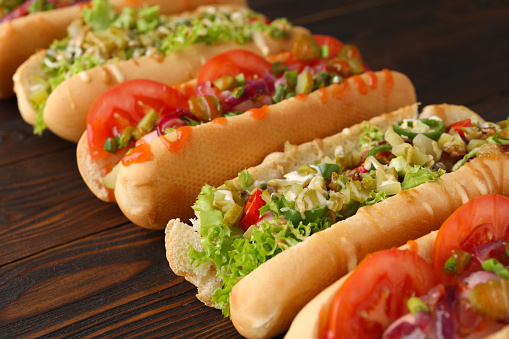 Different tasty hot dogs on wooden table, closeup