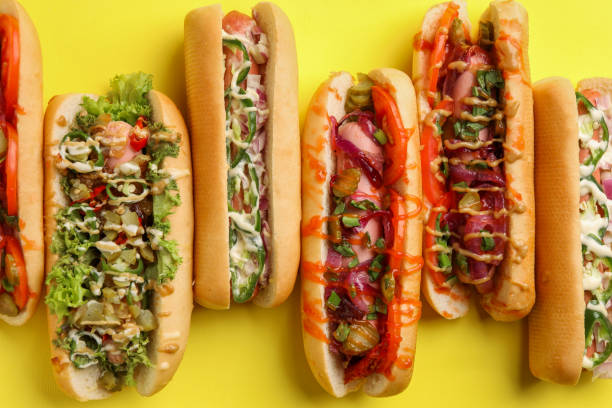 istock Delicious hot dogs with different toppings on yellow background, flat lay 1865522556