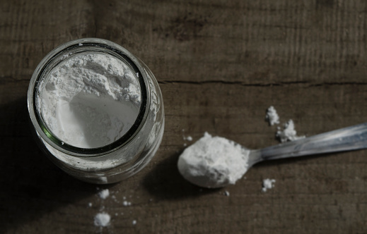 baking soda, multipurpose or baking powder. Viewed from above on wooden background. on a spoon in a glass jar