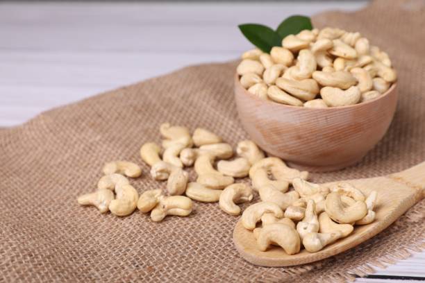 istock Tasty cashew nuts and green leaves on table, closeup. Space for text 1865530698