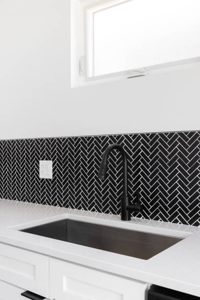 istock A kitchen sink detail with a black faucet and black herringbone tile backsplash. 1865546012
